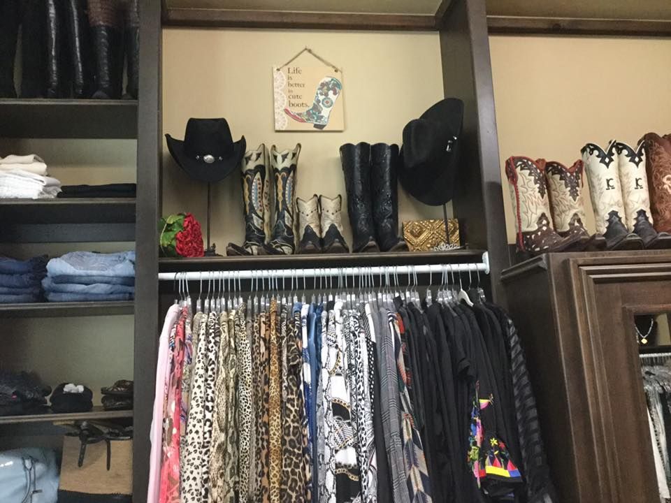 Closet with clothes, boots, and hats on display, brown shelving with tan walls.