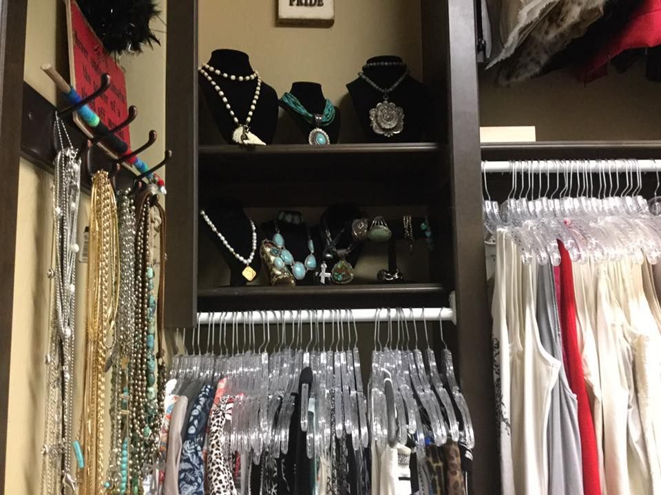 Closet with jewelry display on shelves and hanging necklaces; clothing hangs on the right.