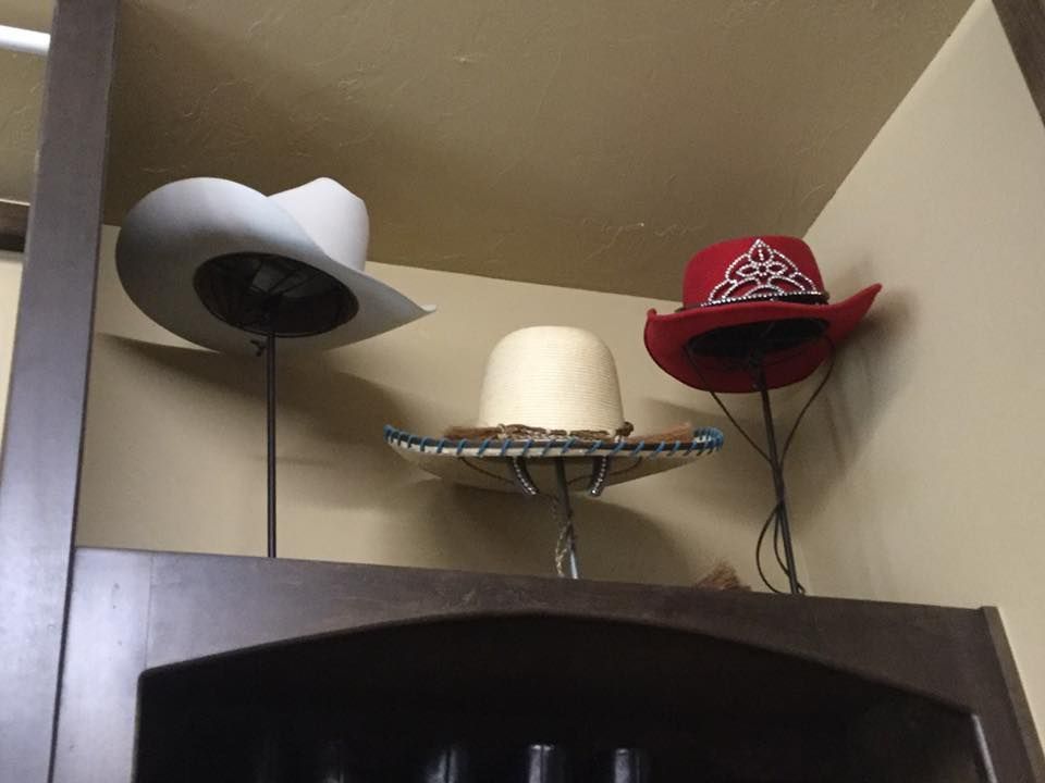 Three hats on display: white cowboy hat, beige hat, and red embroidered hat.