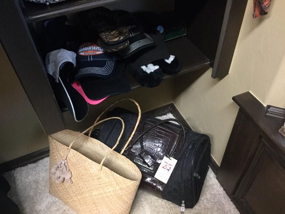 A closet with bags and shoes on a shelf and a straw tote bag on the floor.