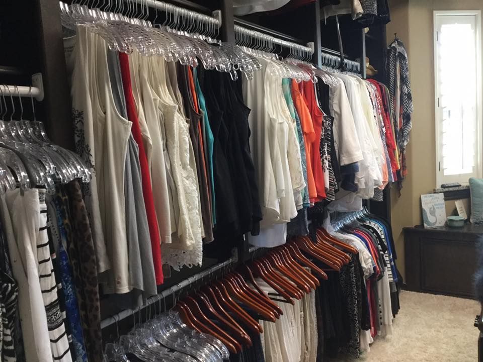 Clothes hanging in a closet. White, black, red, and patterned shirts on clear and wooden hangers.