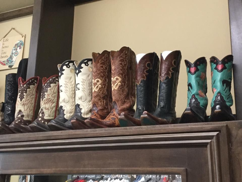 Row of decorative cowboy boots displayed on a shelf. Boots vary in color, with ornate designs.