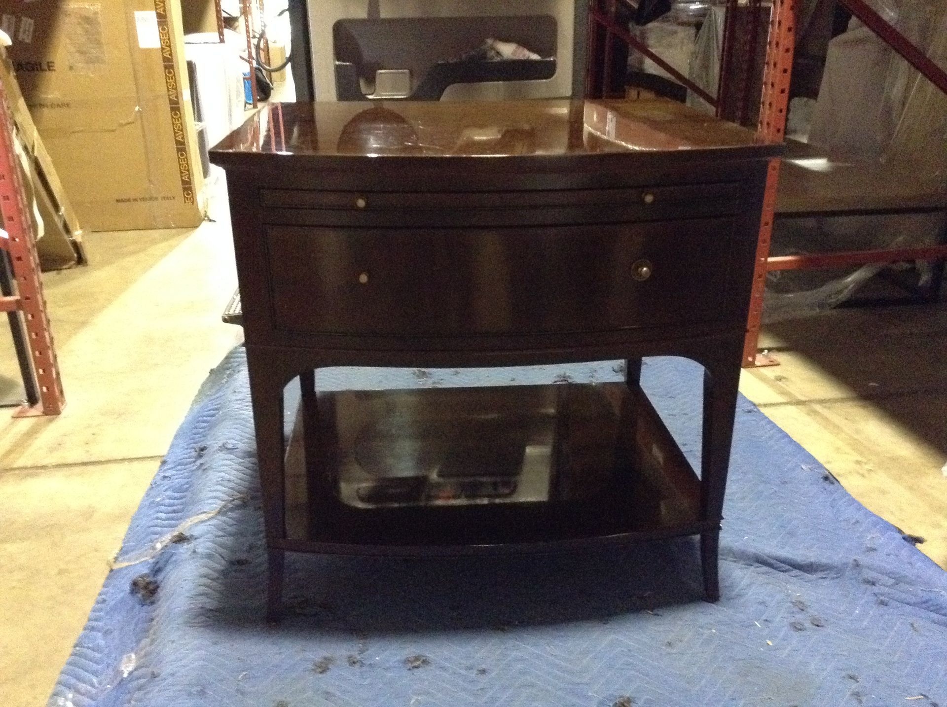 Dark wood antique table with drawers and a bottom shelf, sitting on a blue tarp.