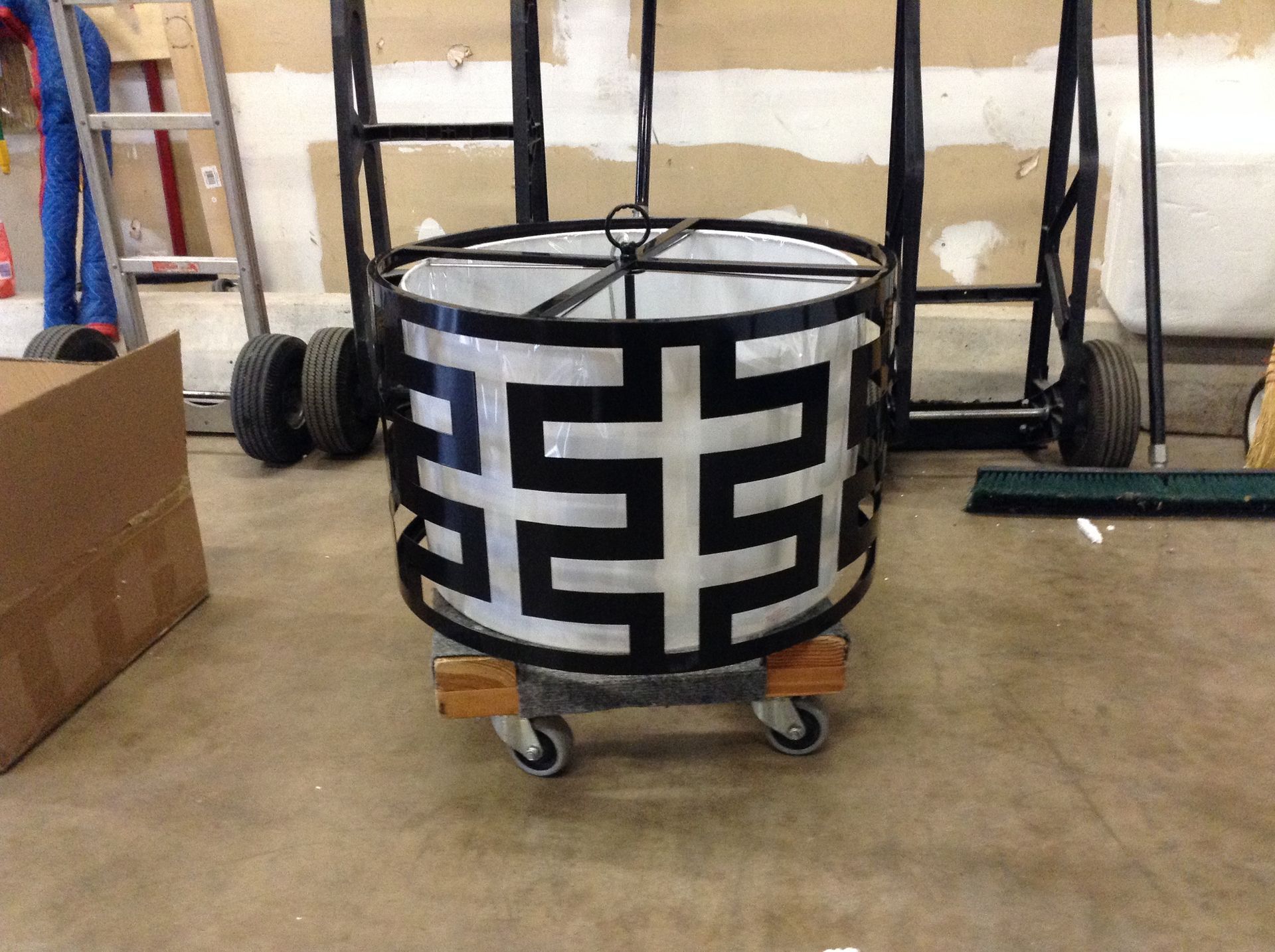 Black and silver geometric lantern on wheels, in a garage.