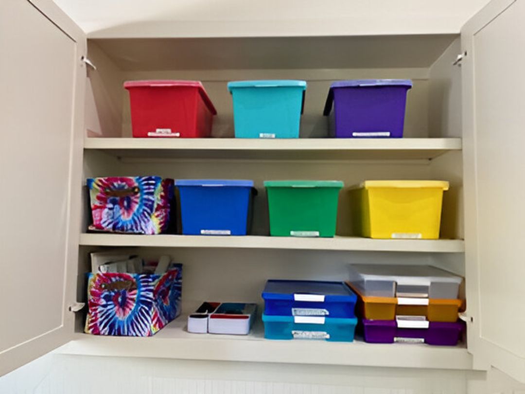 A cabinet with shelves holding colorful storage bins and containers, organized neatly.