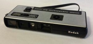 A kodak camera is sitting on a white surface.