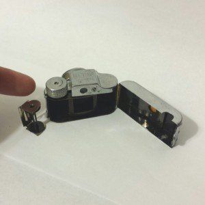 A person is holding a lighter in the shape of a camera.