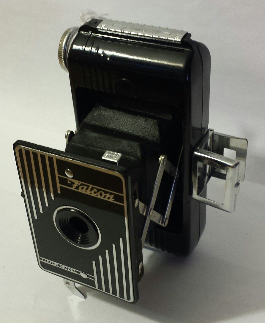 A black and gold falcon camera sitting on a white surface