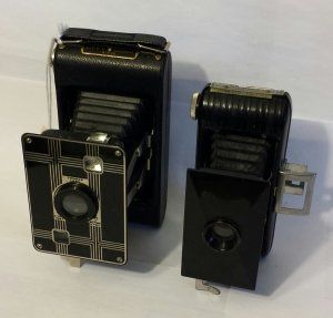 Two old cameras are sitting next to each other on a table