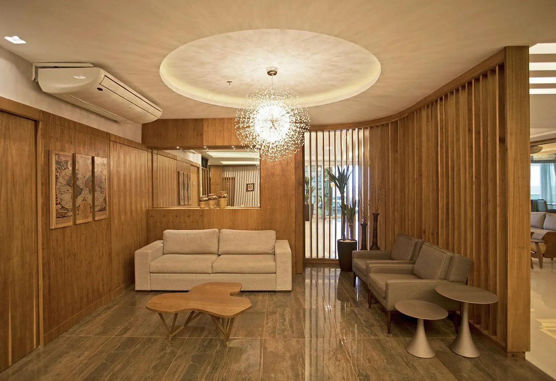 Sala de estar moderna com painéis de madeira, sofá bege, luminária pendente e piso de mármore.