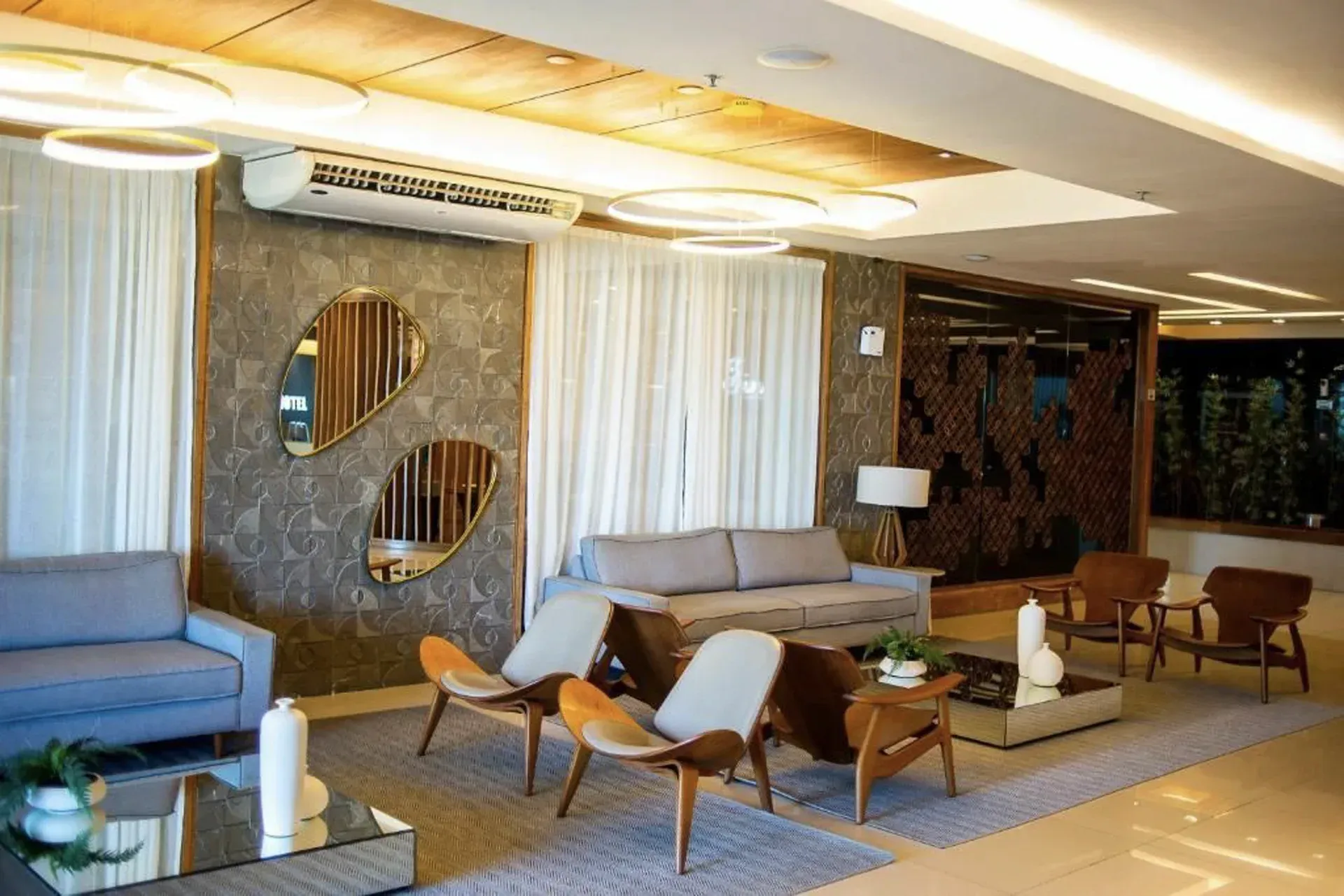 Sala de estar moderna com sofás, cadeiras e iluminação aconchegante no teto, em um elegante espaço interno.