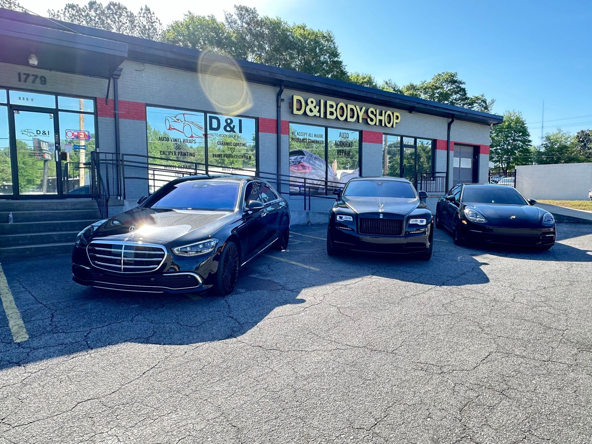 Three black cars parked outside D&I Book Shop on a sunny day
