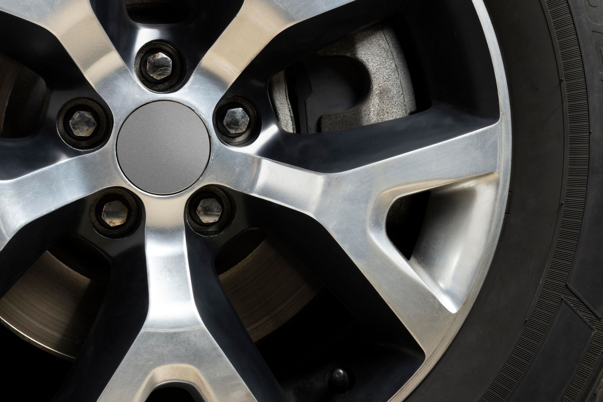 Close-up of an orange classic car’s wheel with chrome rim and white-letter tire on wet pavement