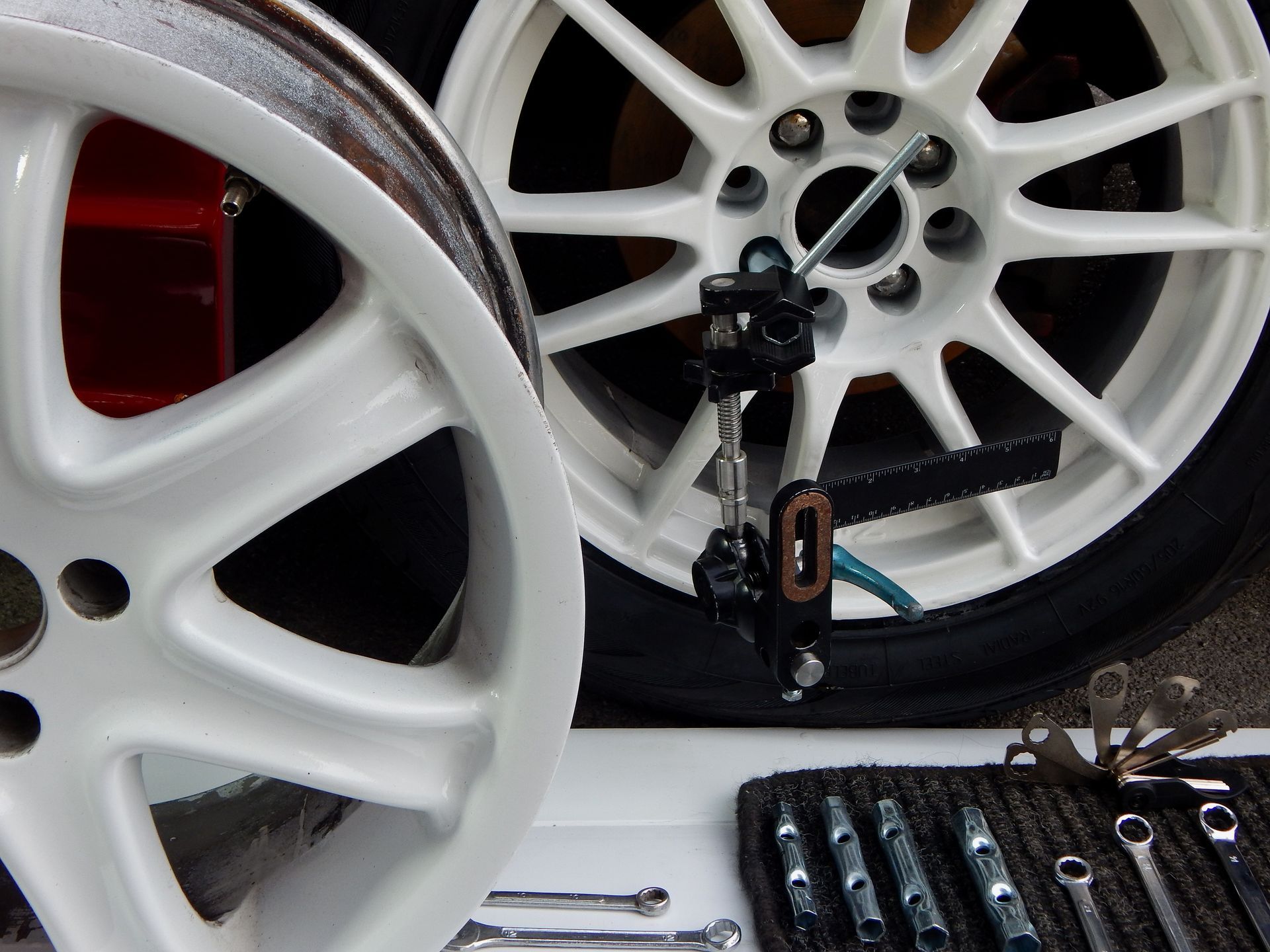 Close-up of an orange classic car’s wheel with chrome rim and white-letter tire on wet pavement