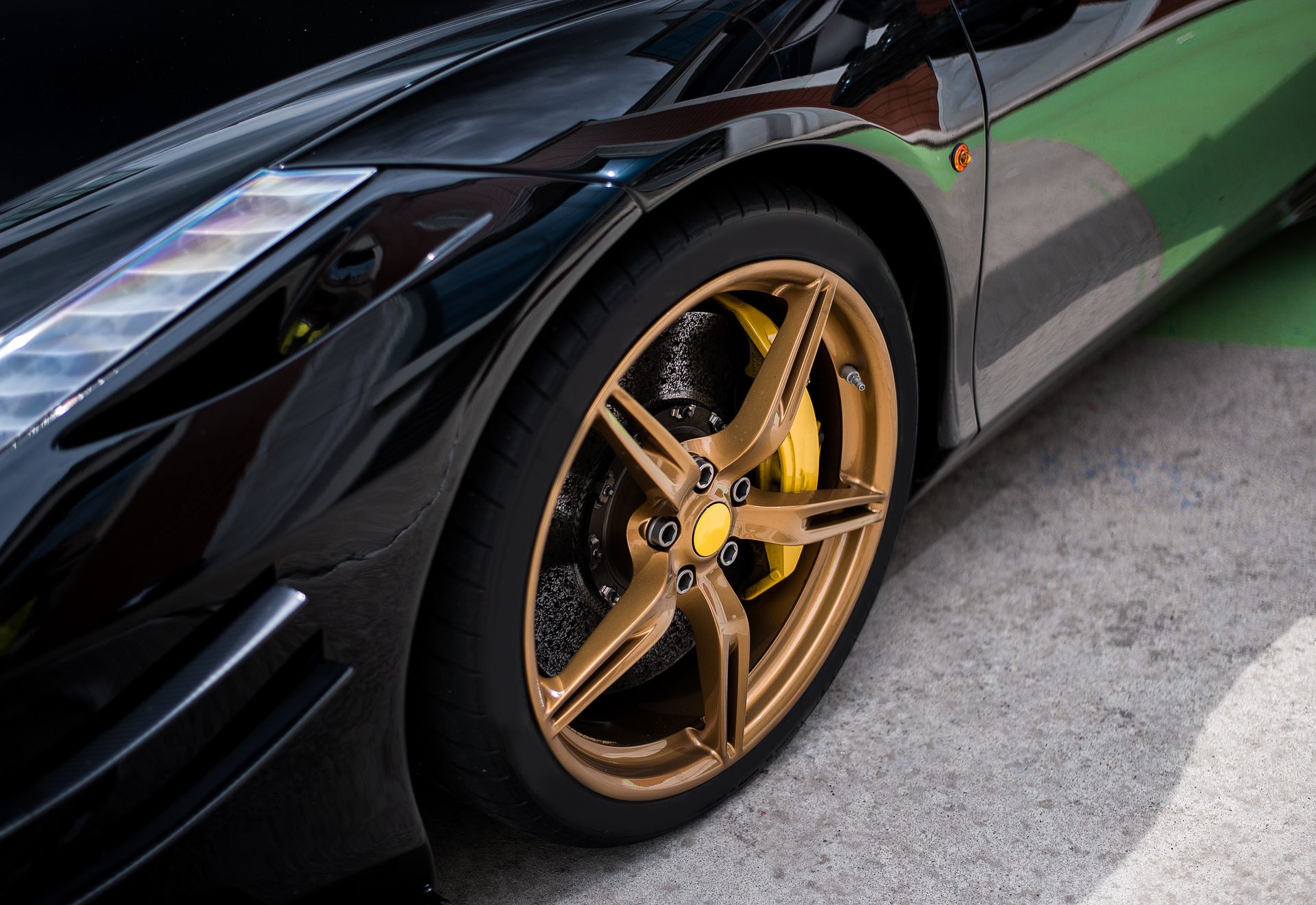 Close-up of an orange classic car’s wheel with chrome rim and white-letter tire on wet pavement