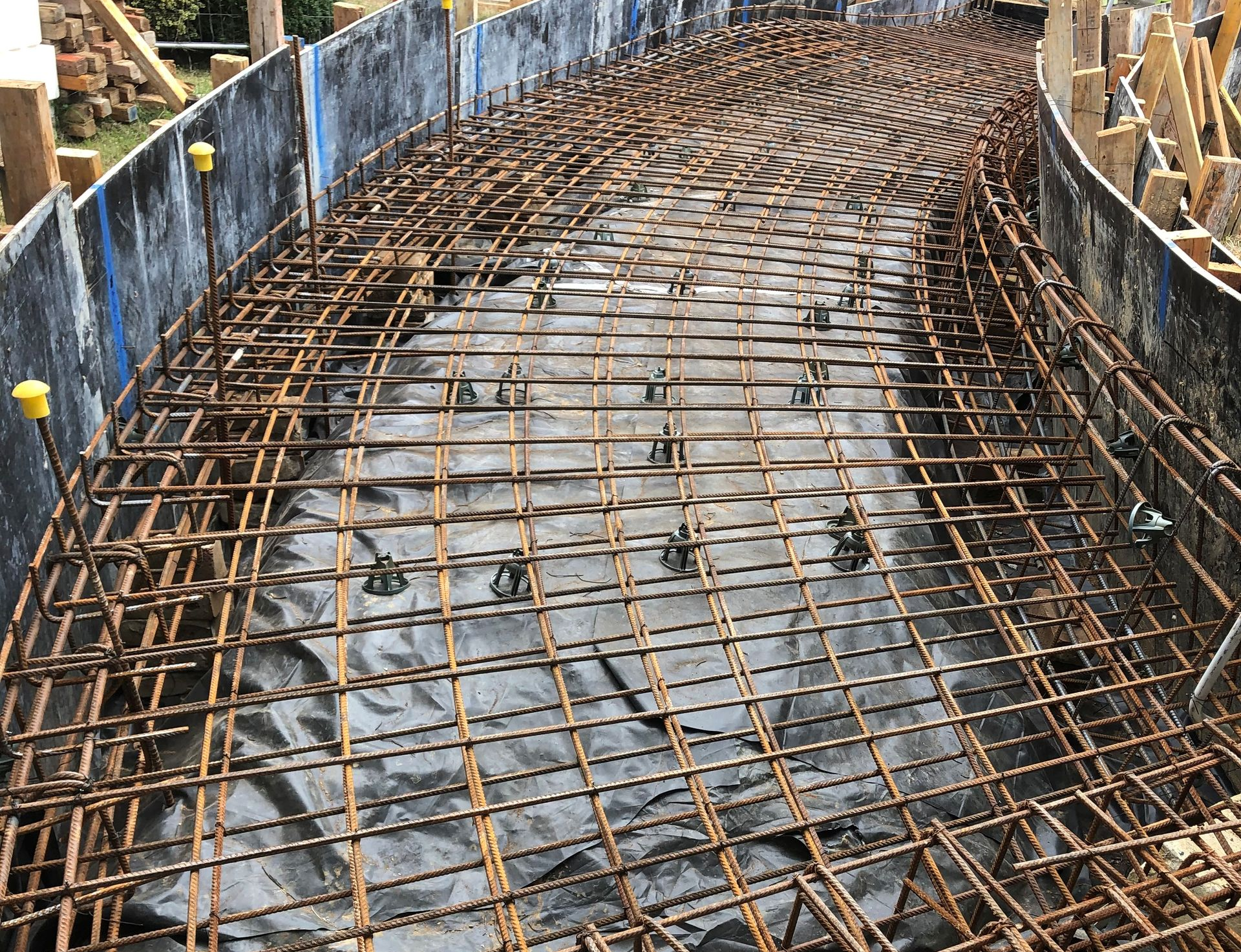 Construction workers installing steel beams on a building frame with cranes and a lift.