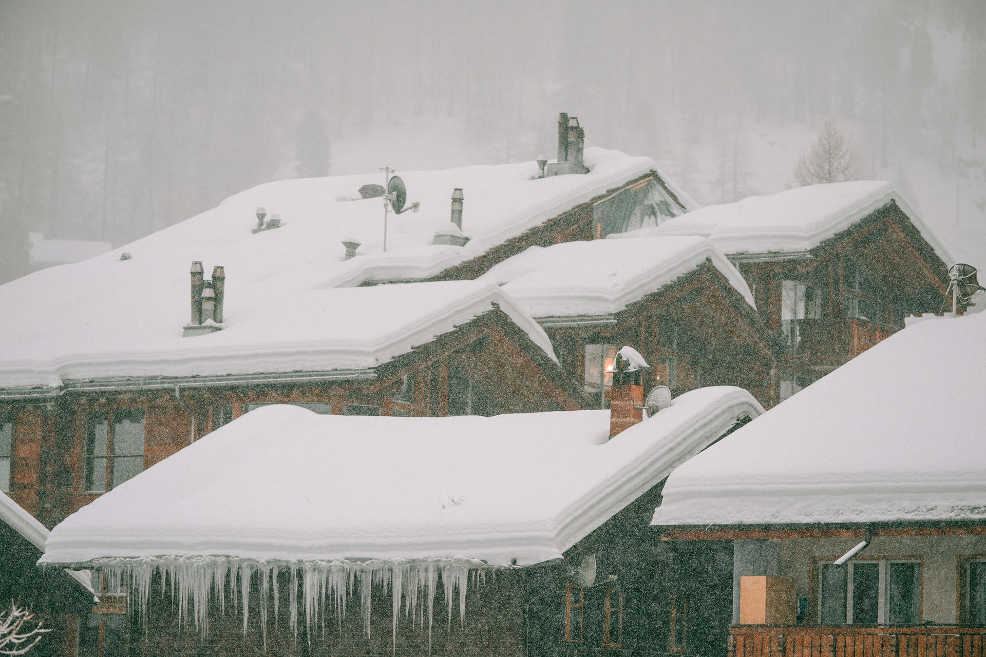 Snow-covered rooftops in a neighborhood during heavy snowfall