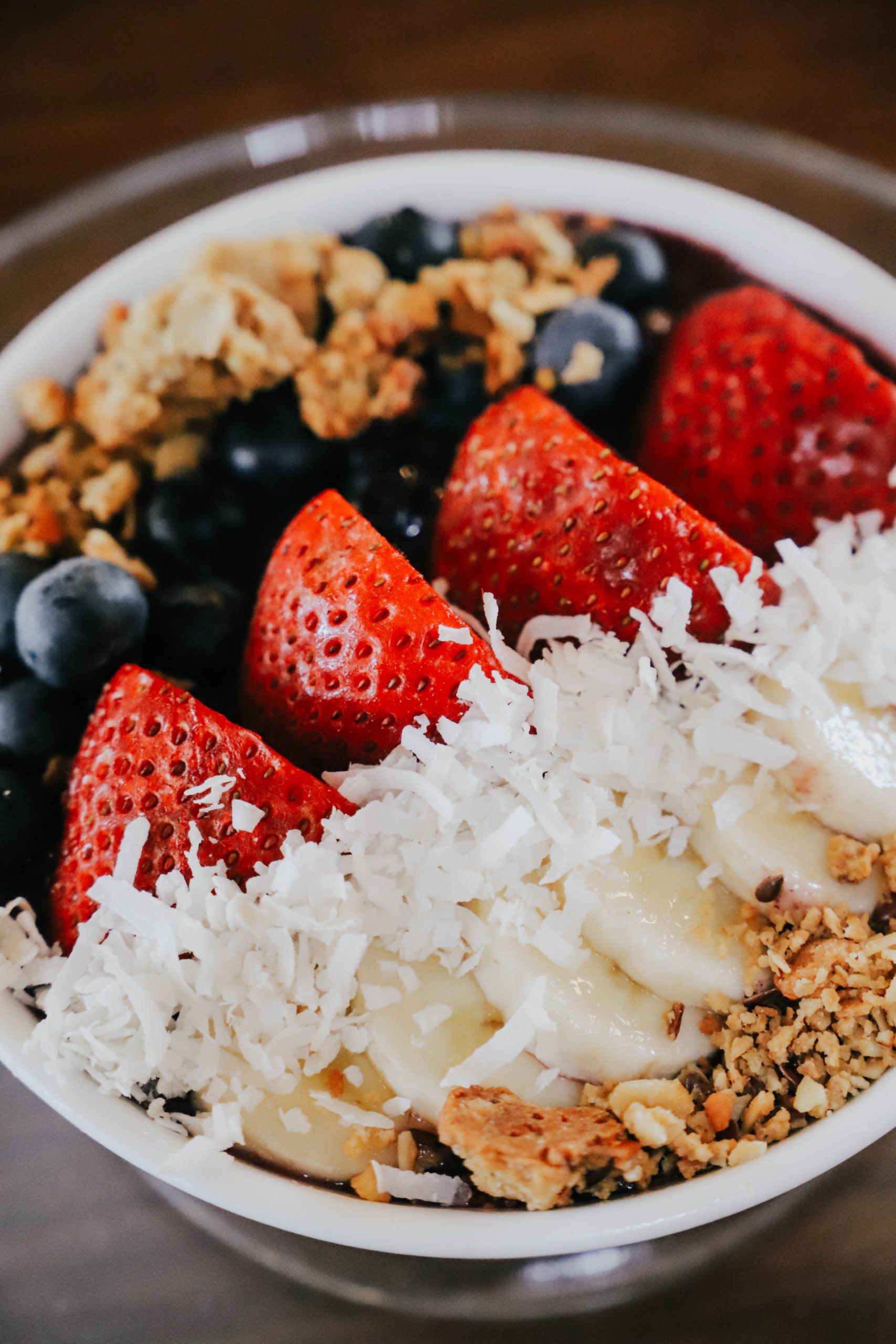 A bowl of fruit with coconut and granola on top