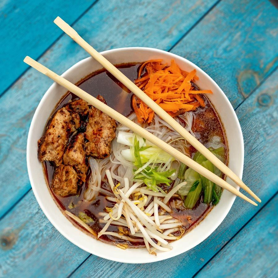 A bowl of soup with chopsticks on a blue table