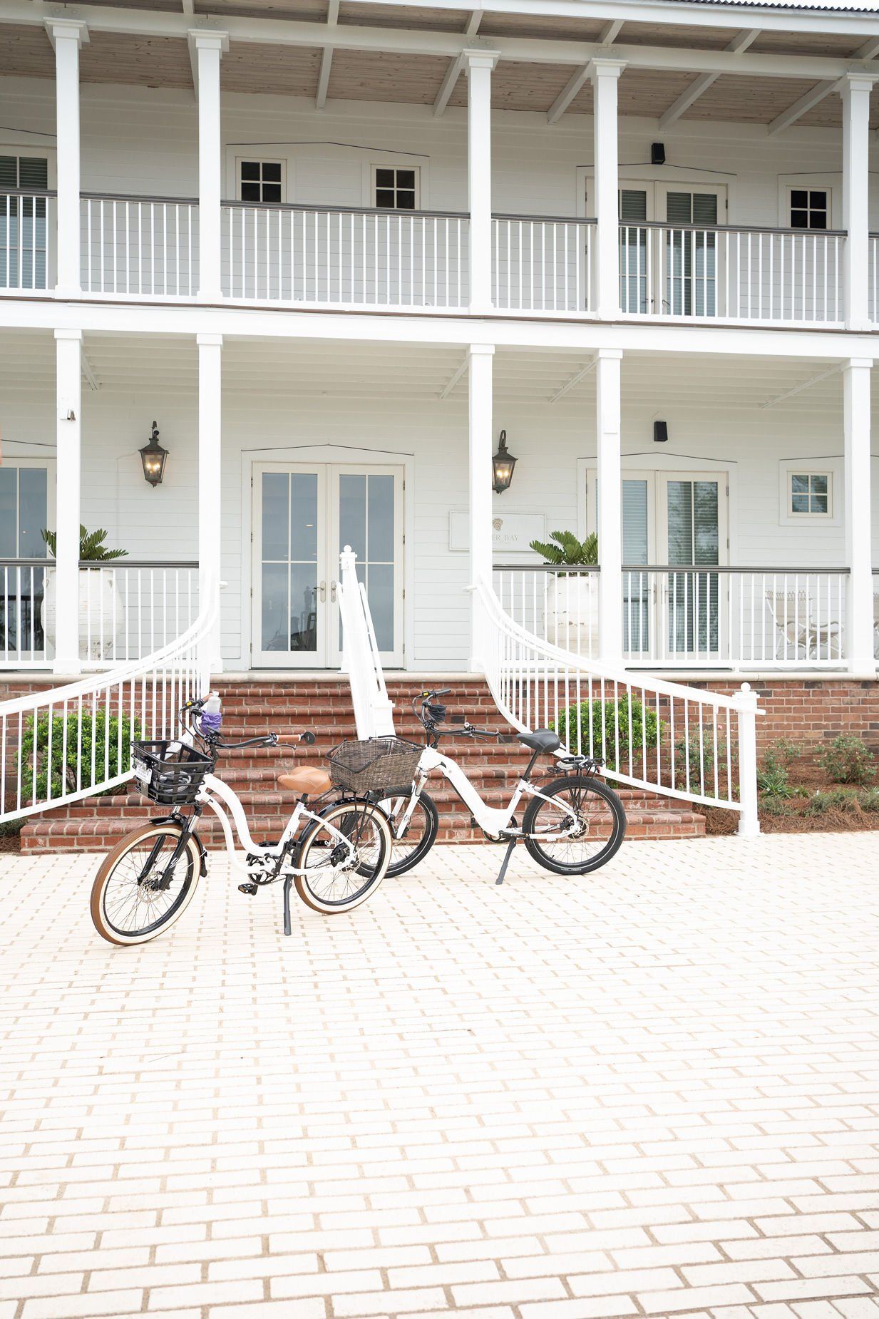 Two bicycles are parked in front of a white building