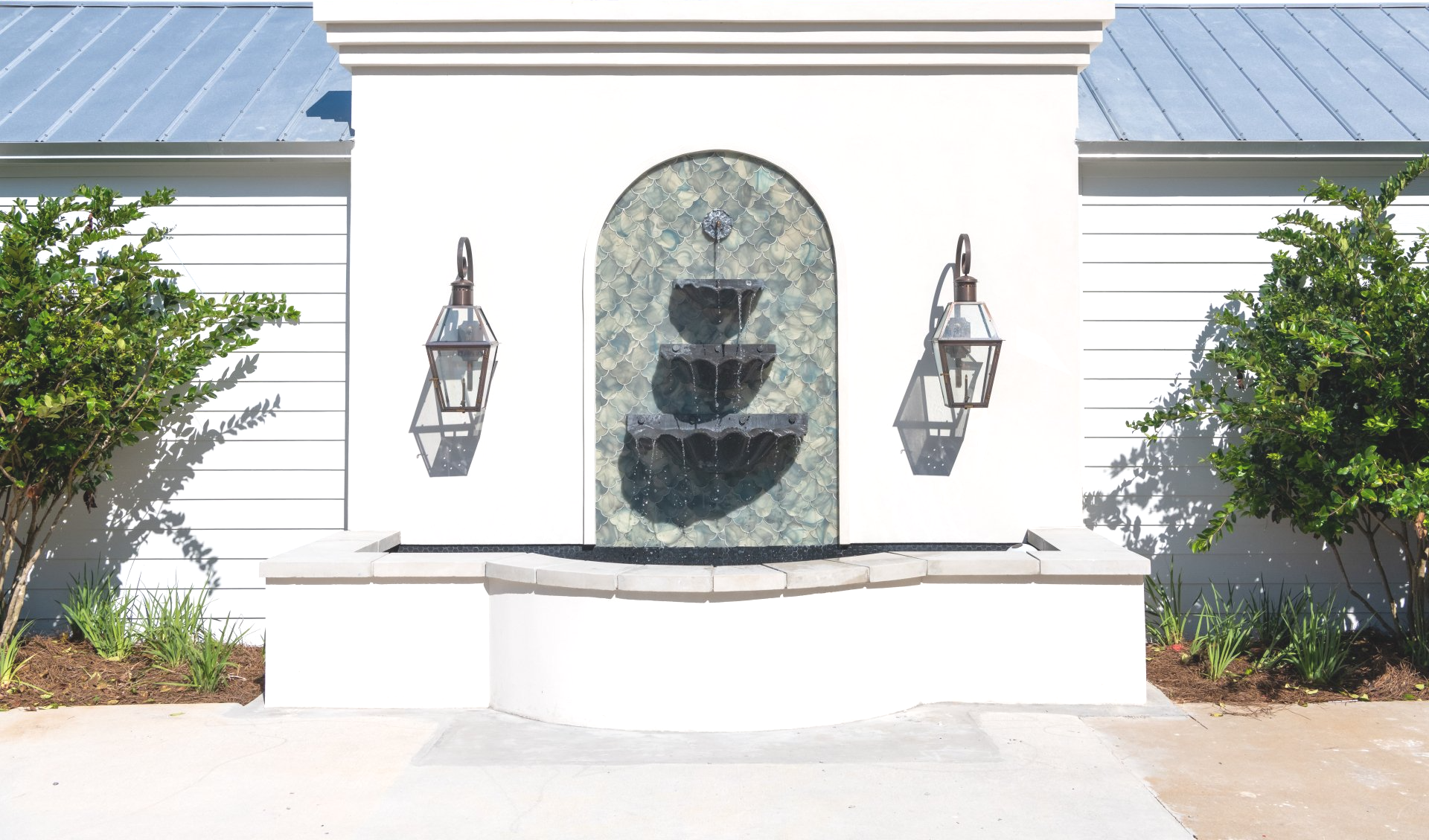 A white wall with a fountain and lanterns on it