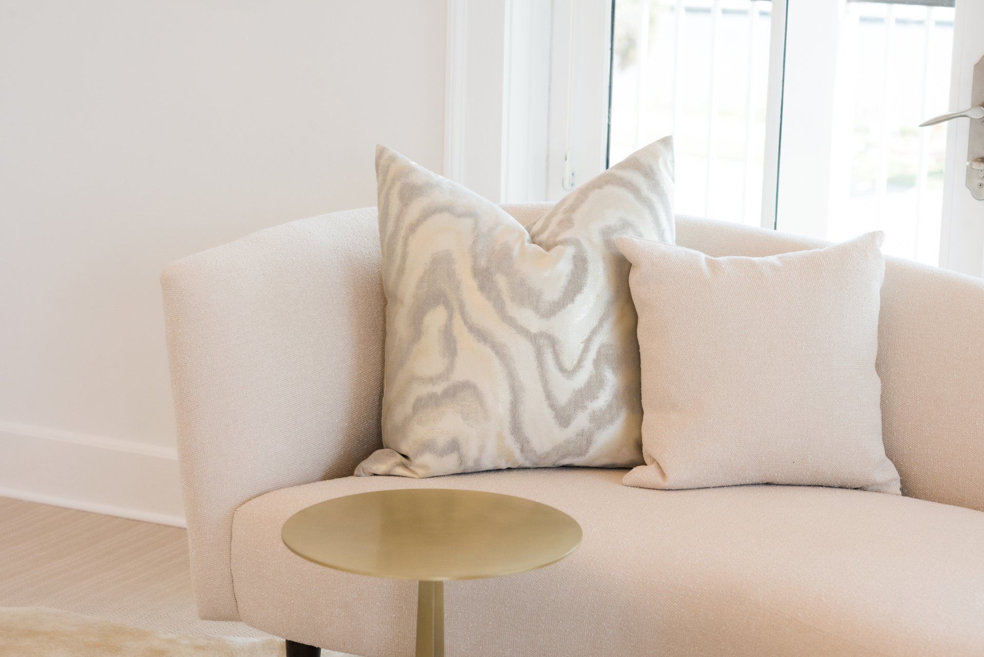 A couch with two pillows on it and a side table in the lobby of oyster bay boutique hotel 