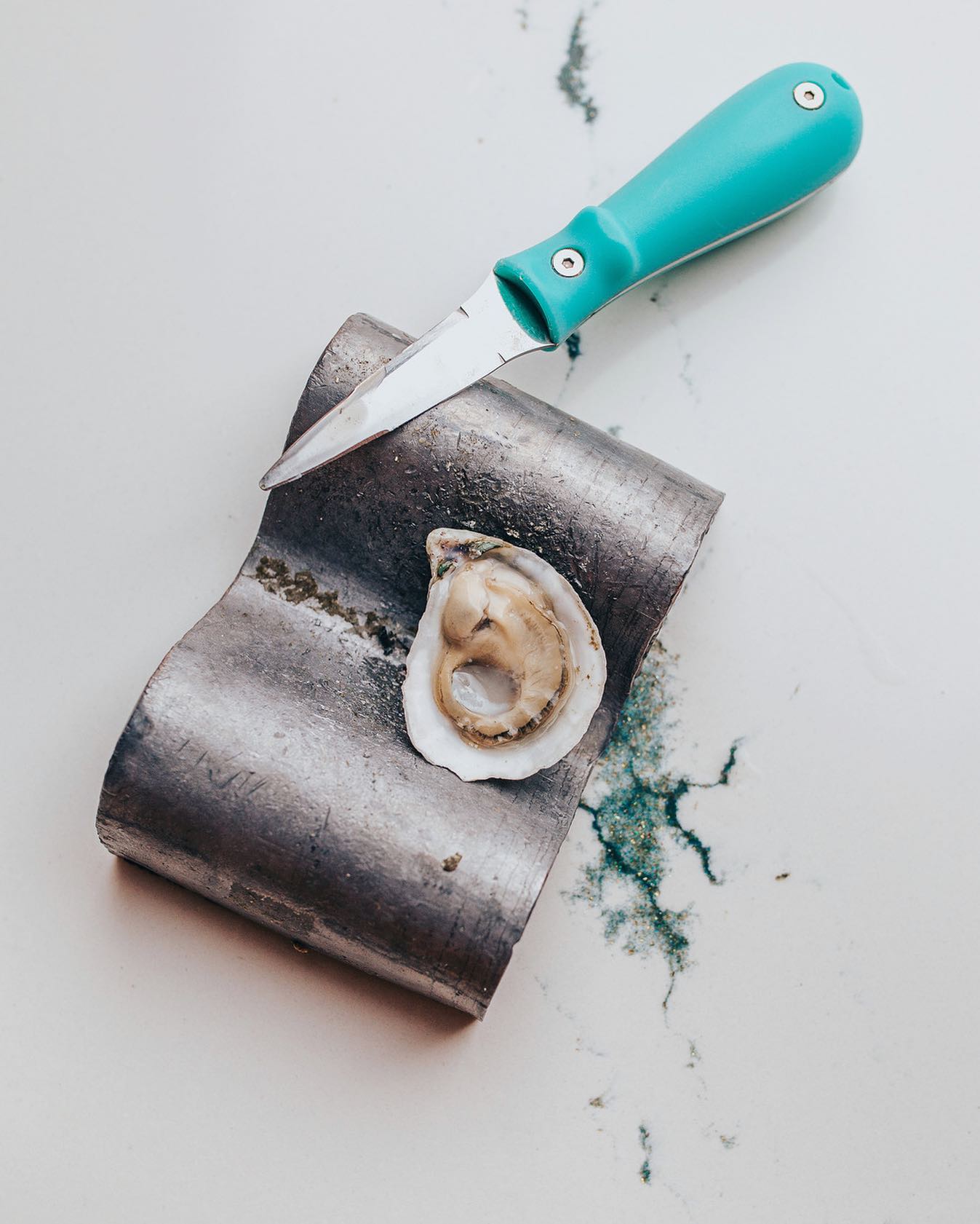 a finely presented raw oyster  on a wavy plate