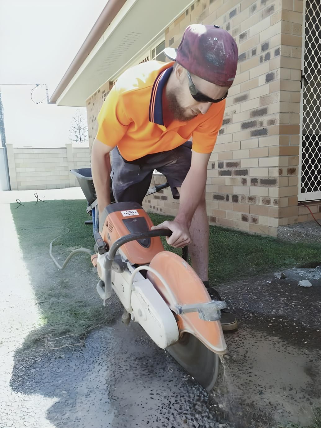 A Man is Using a Stihl Chainsaw to Cut a Hole in the Ground — Handyman Bundaberg In Burnett Heads, QLD