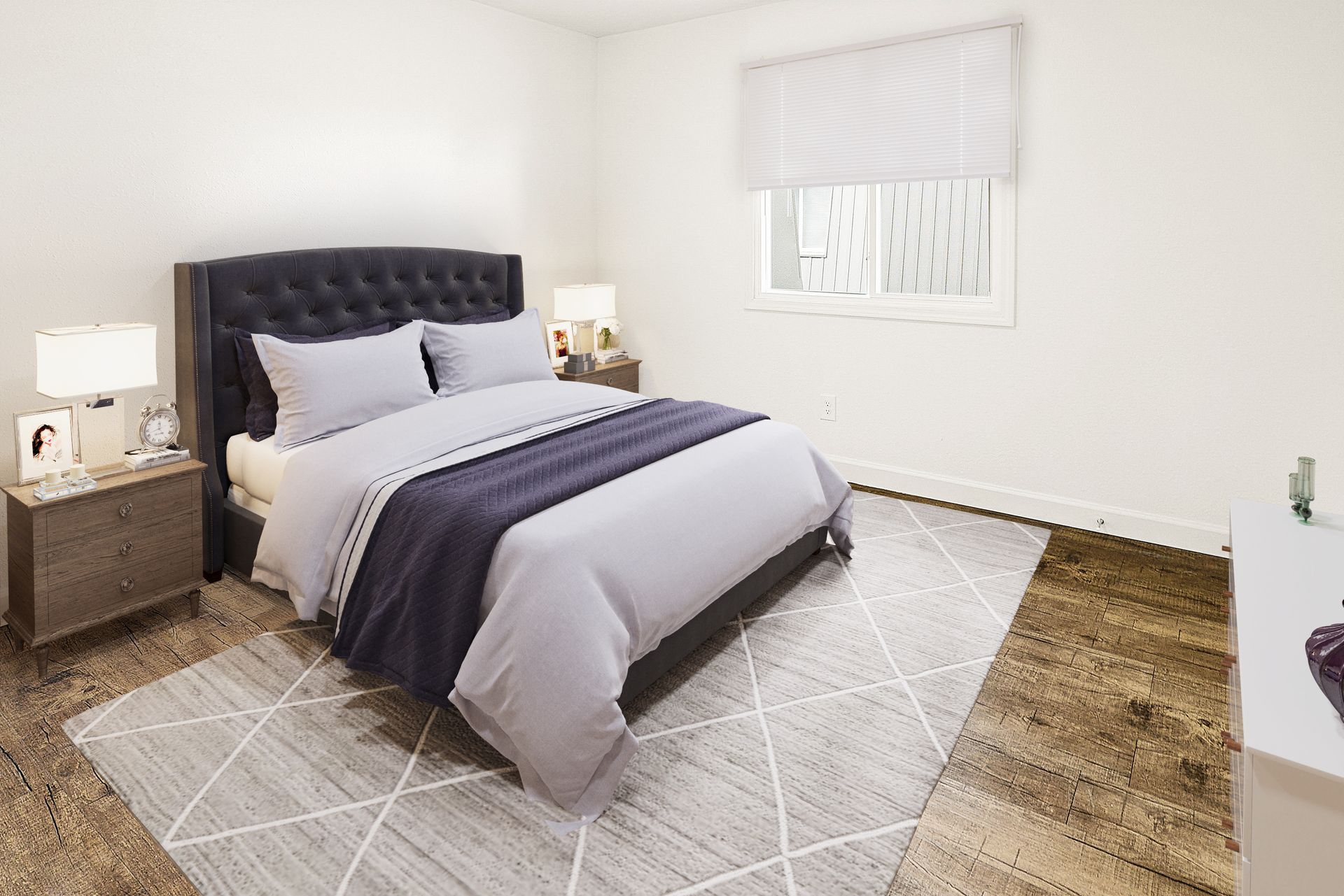 Bright bedroom with a dark upholstered bed, gray bedding, bedside tables, and a tiled floor rug.