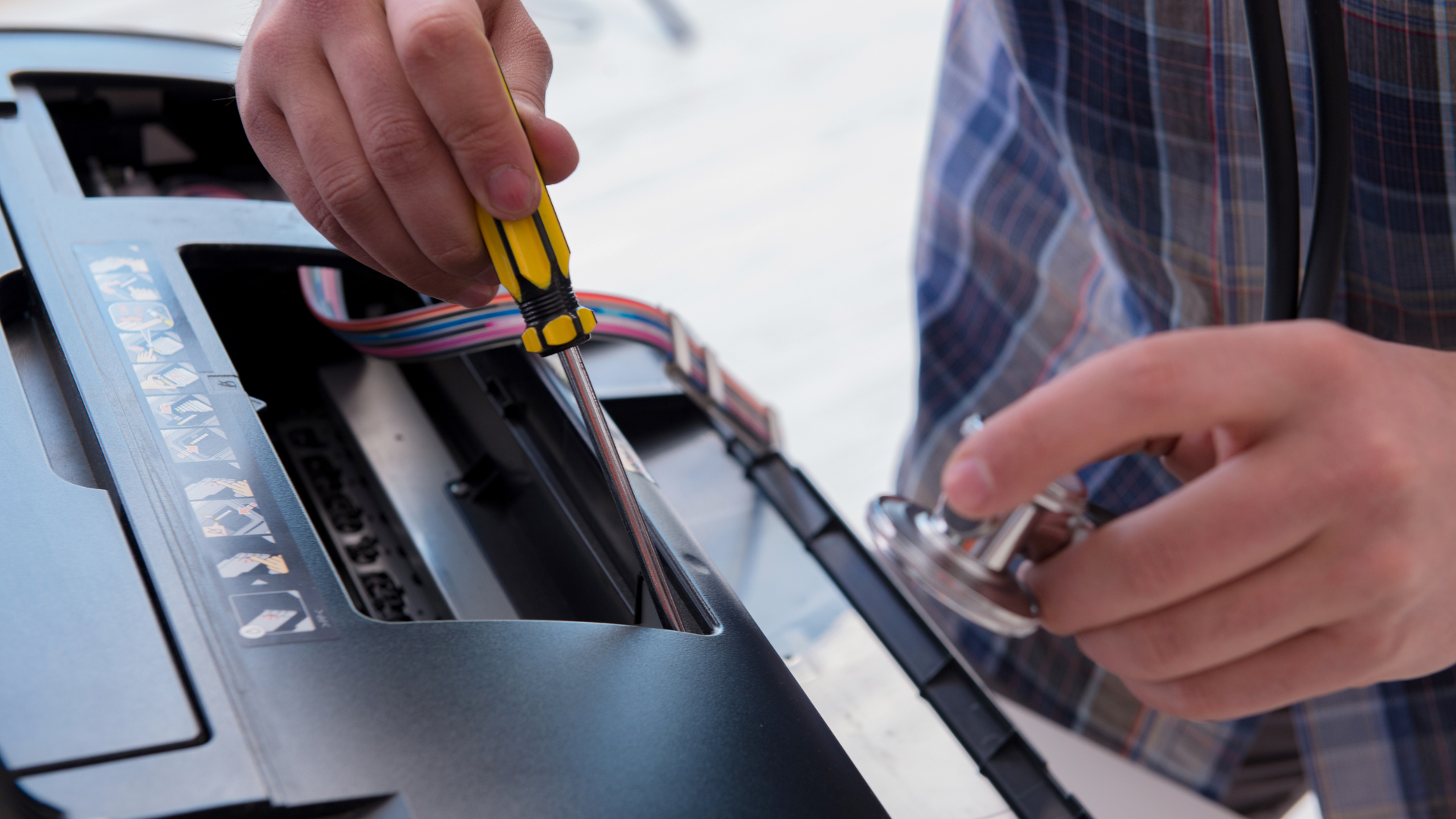 A man is fixing a printer with a screwdriver.