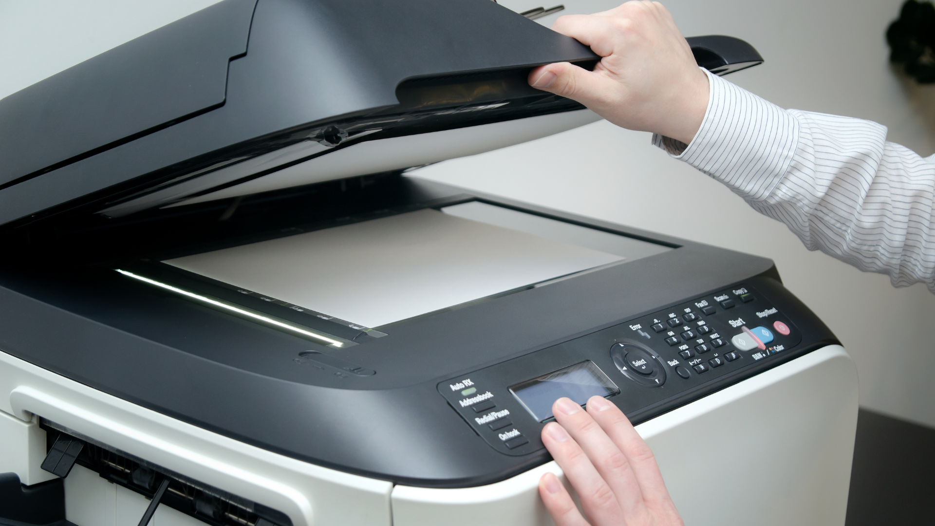 A person is using a copier to scan a piece of paper.