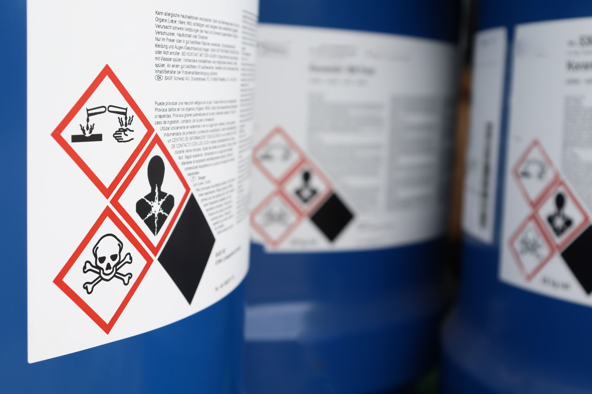 A row of blue barrels with warning labels on them