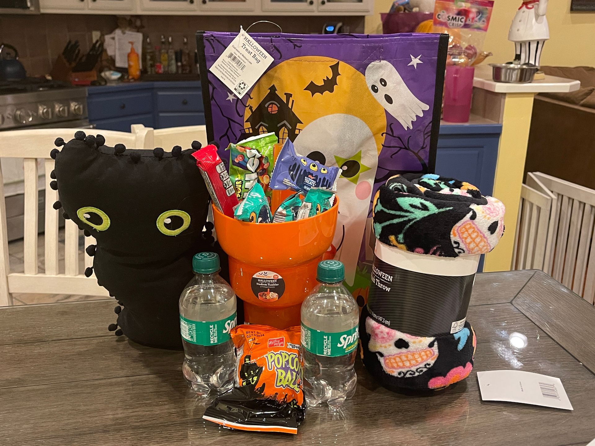 Halloween candy display with black cat, pumpkin bucket, decorated treat jars, and spooky backdrop