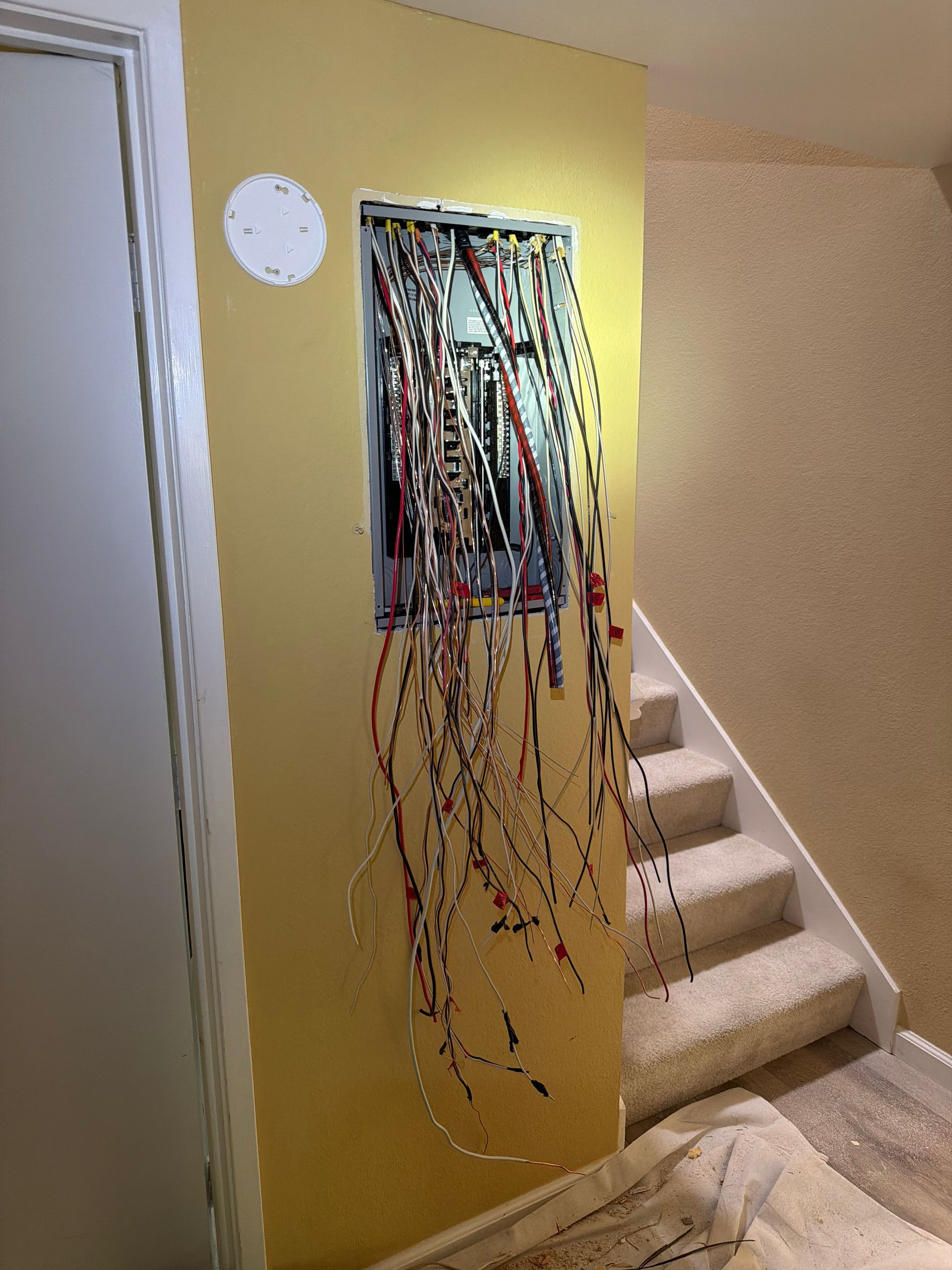 Electrical junction box with exposed colored wires mounted on a concrete ceiling
