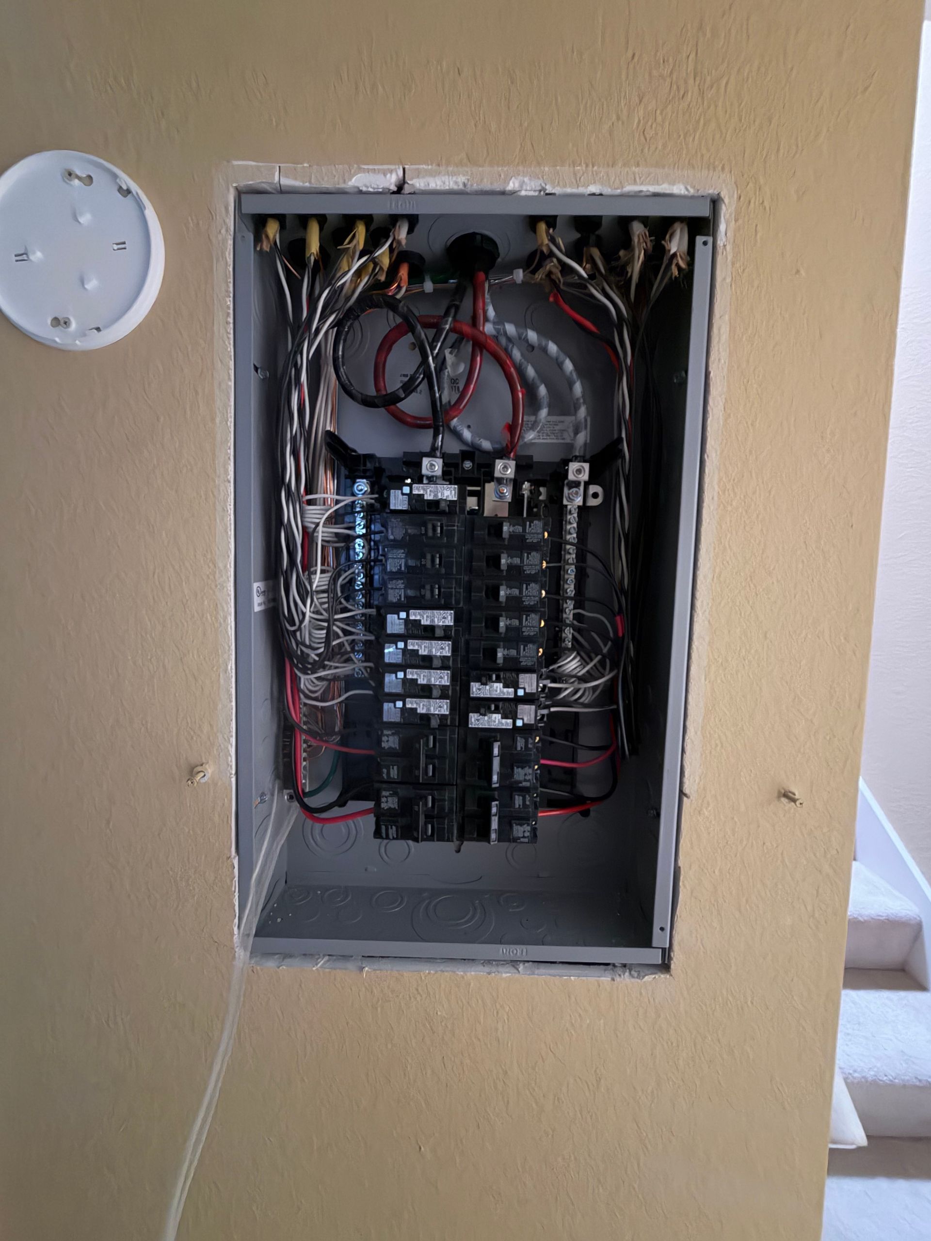 Electrician wiring cables into a brick wall with pliers and gloves