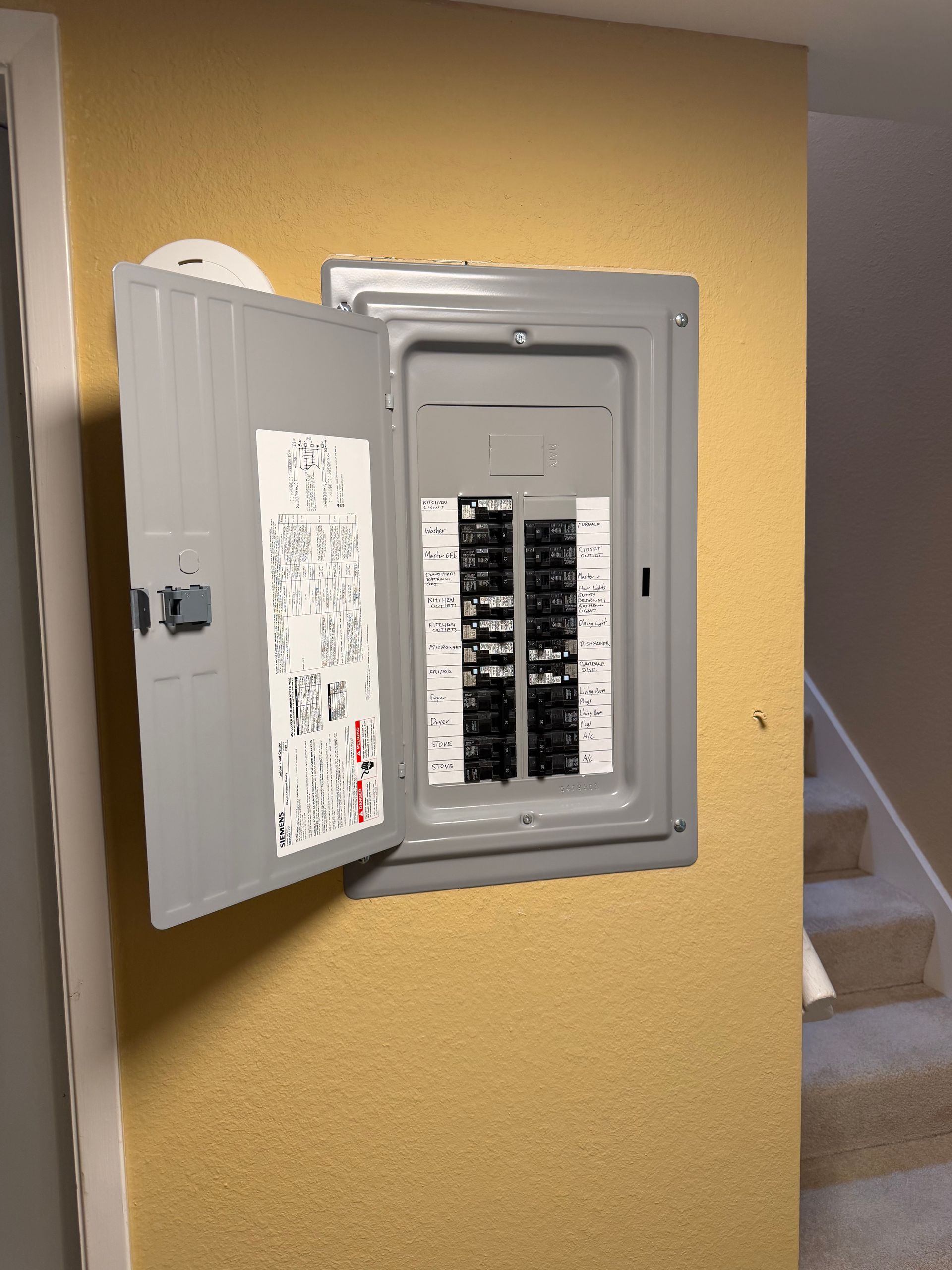 Open electrical panel with exposed multicolored wiring and terminal blocks inside a gray metal cabinet.