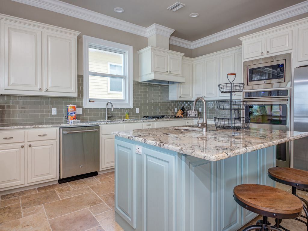 Kitchen with white cabinets, blue island, granite countertops, and stainless steel appliances.