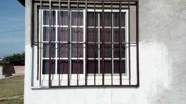 Ventana con rejas de seguridad en una pared de estuco.