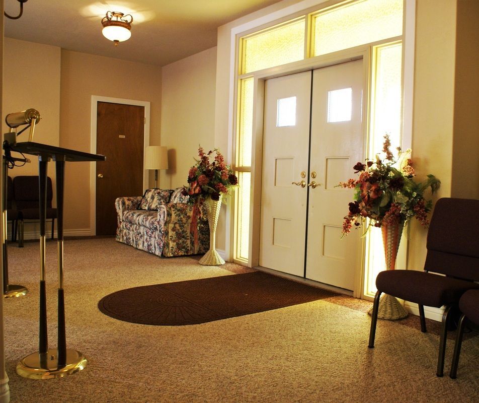 Lobby entrance with double doors, floral arrangements, and chairs in a warmly lit interior.