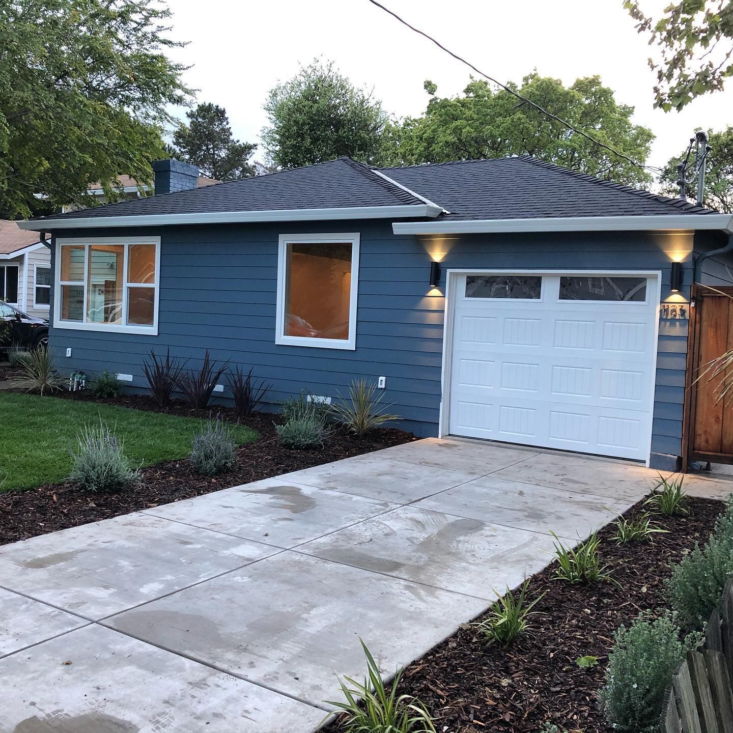 A blue house with a white garage door and a driveway