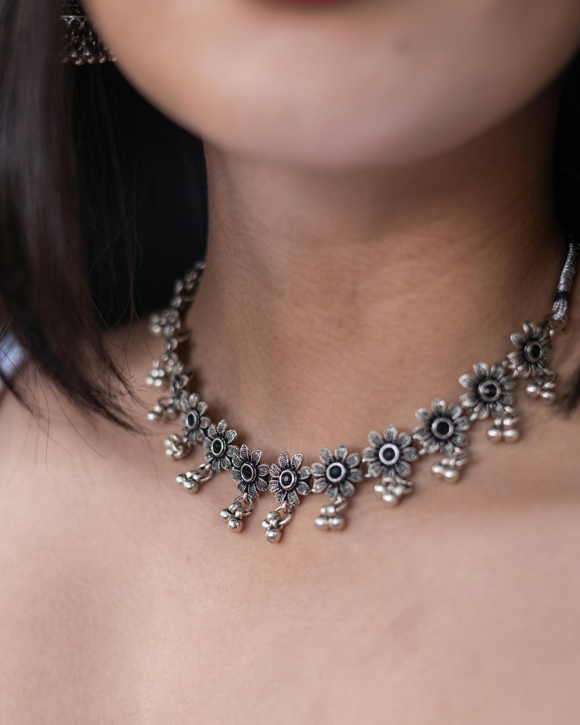 A close up of a woman wearing a necklace and earrings