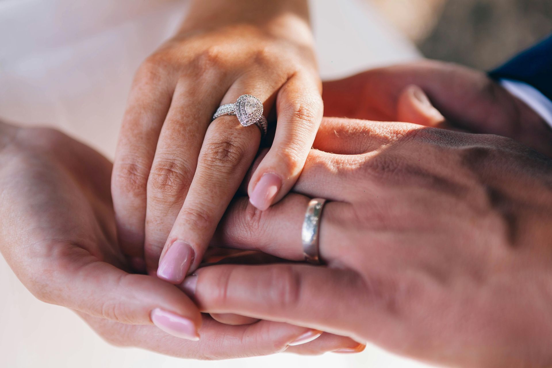 A bride and groom are holding hands with their wedding rings on.
