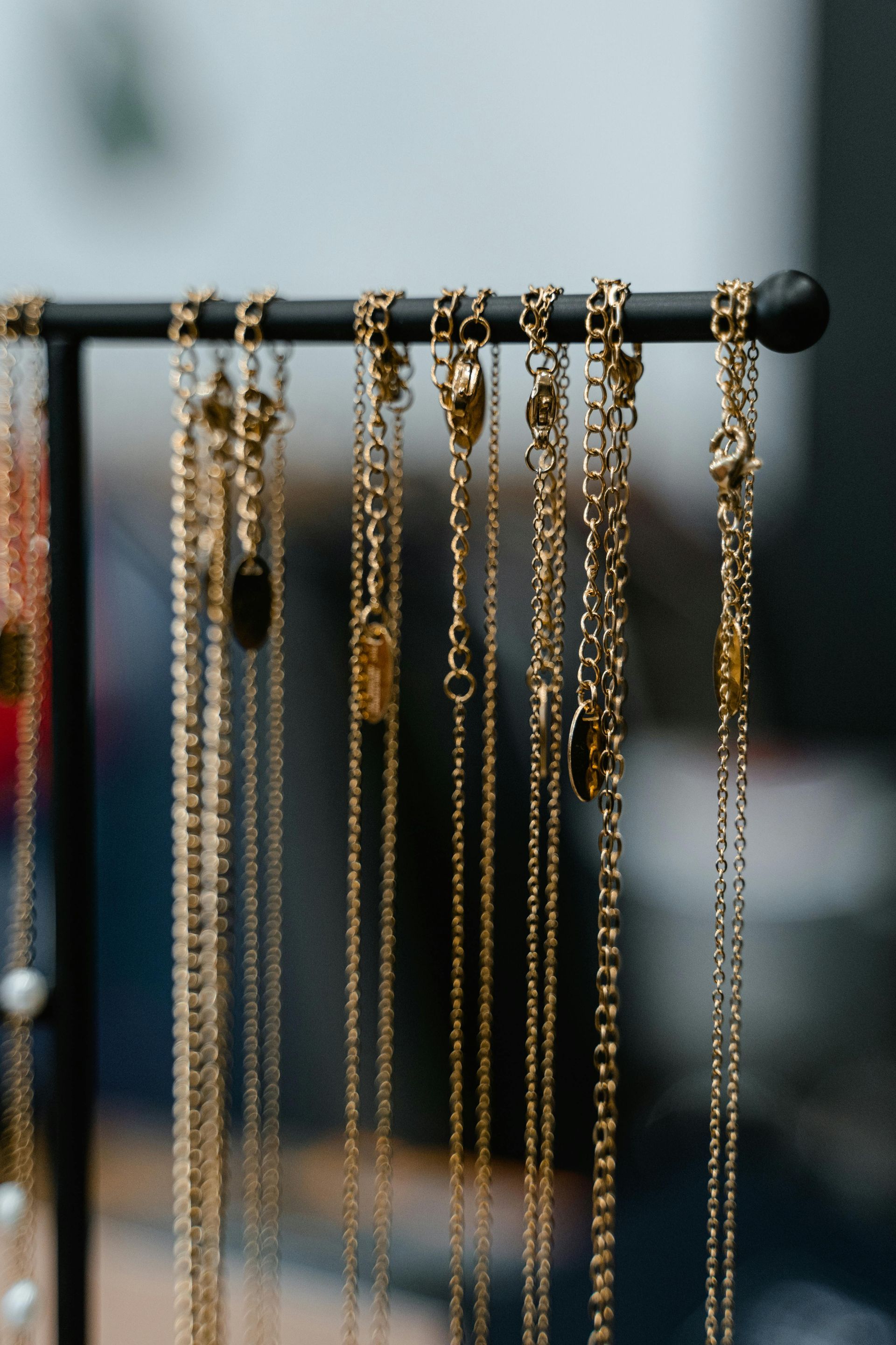 A bunch of gold necklaces are hanging on a rack