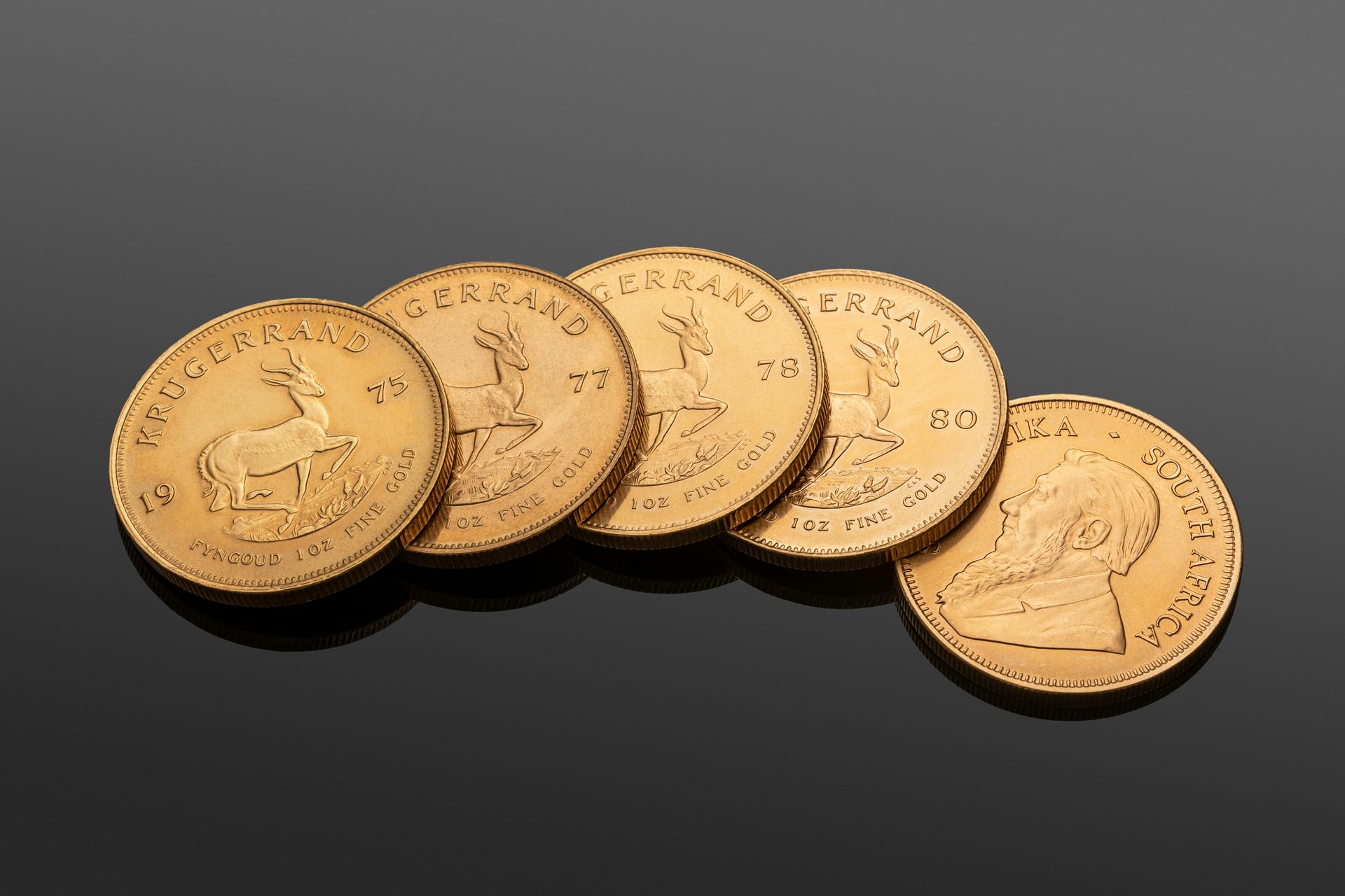 Five gold coins are lined up in a row on a black surface.