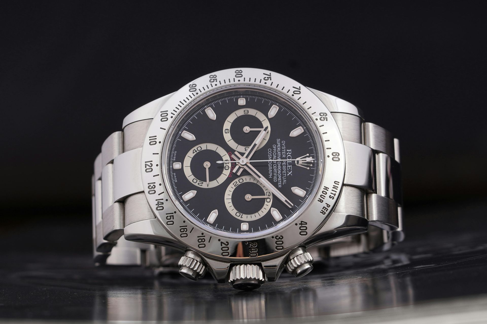 A silver rolex watch with a black face is sitting on a table.