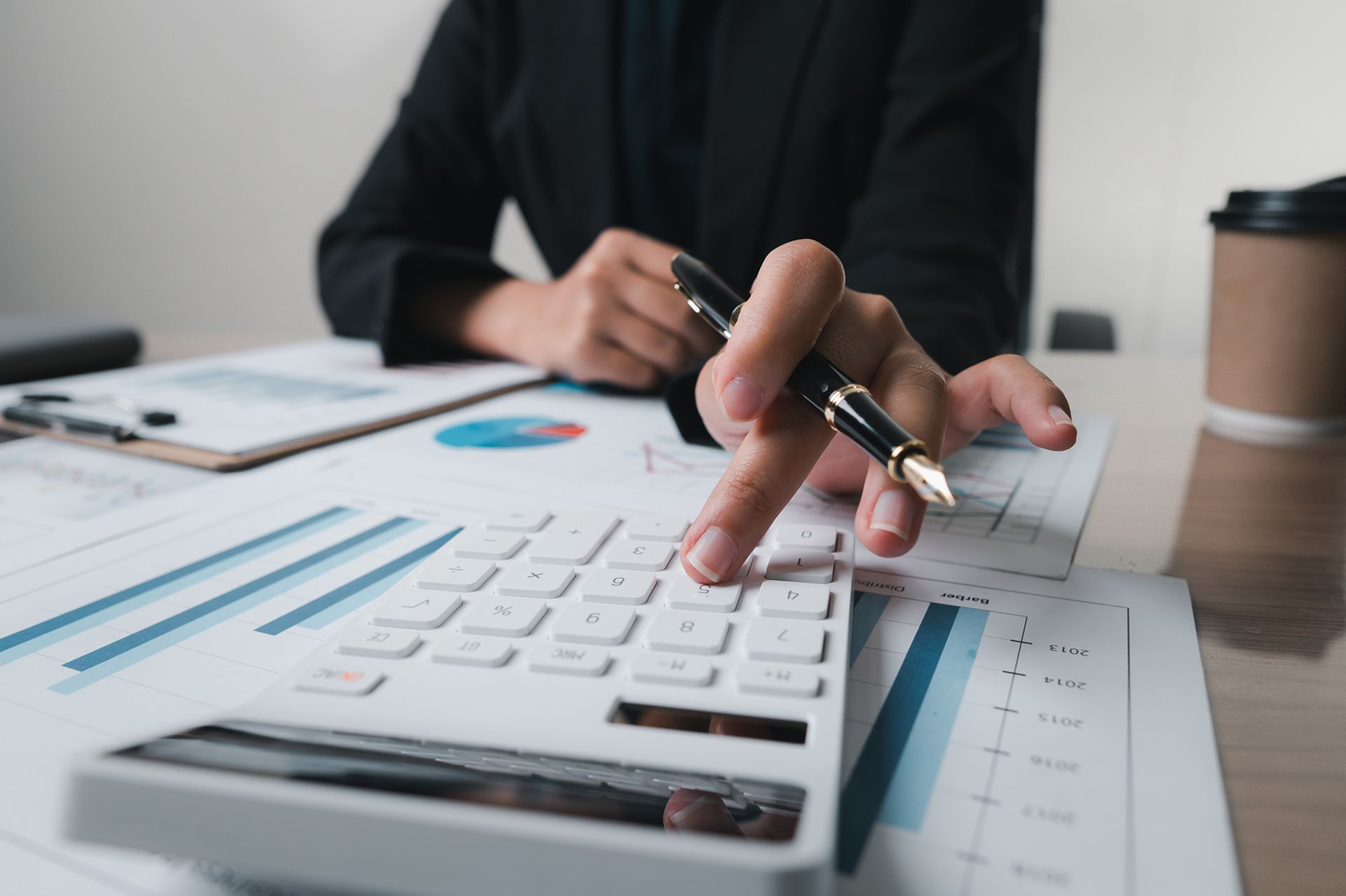 Businessperson using calculator and reviewing financial documents at a desk