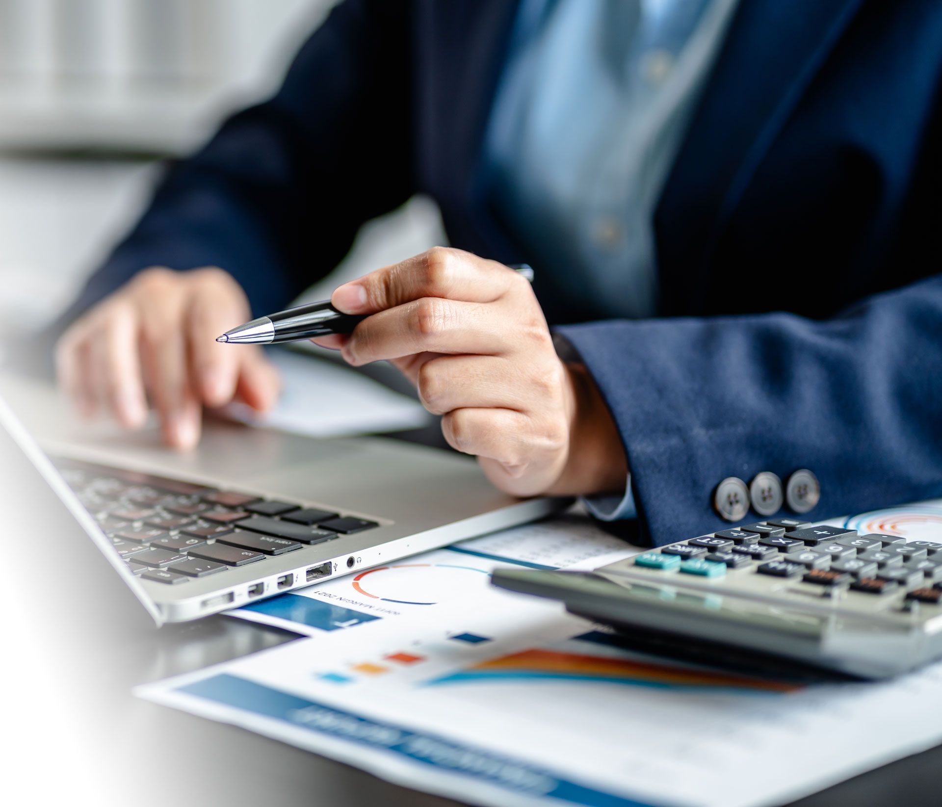Businessperson using a laptop and calculator while reviewing financial documents with a pen