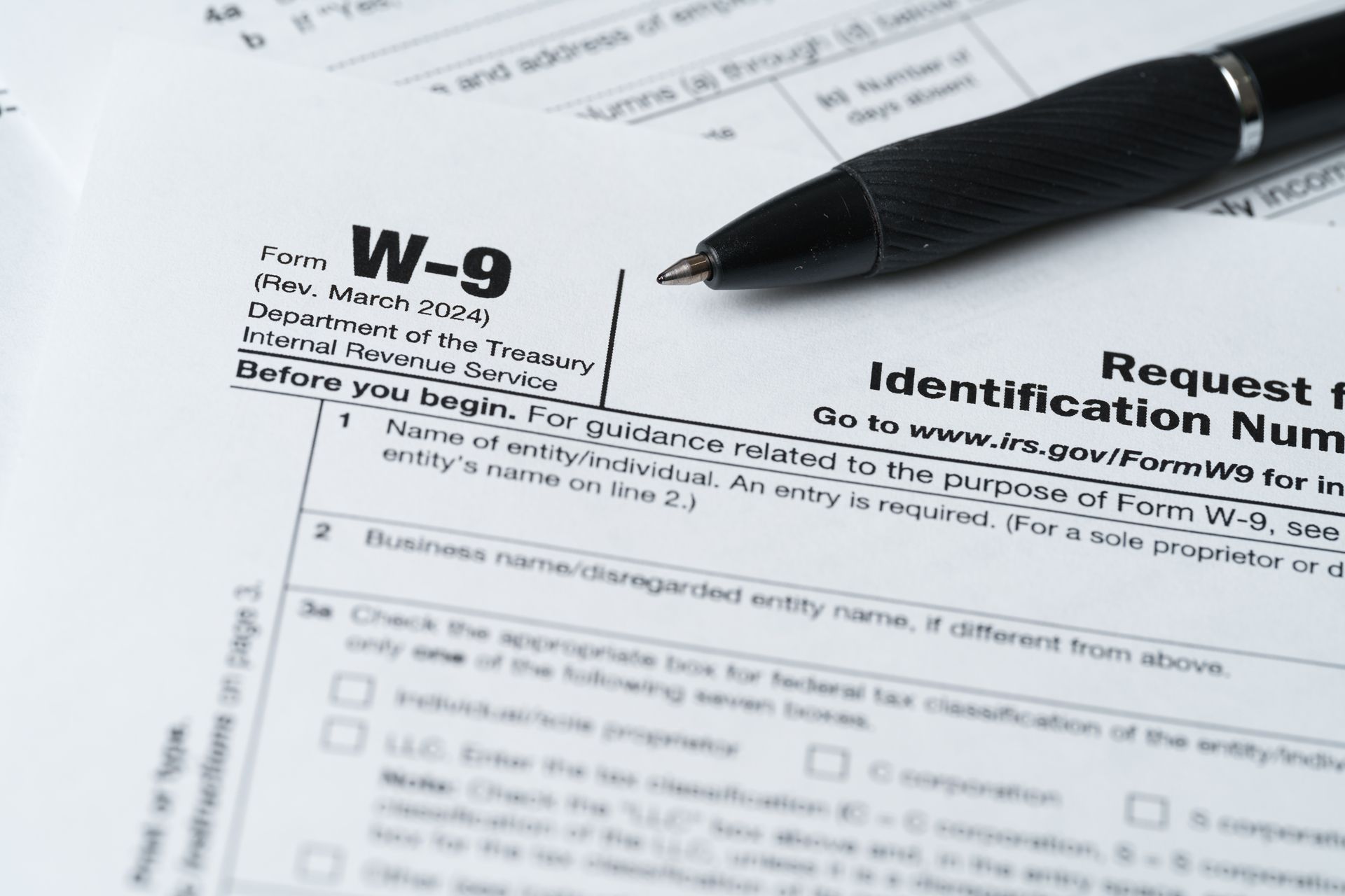 W-9 tax form beside a black pen on a desk