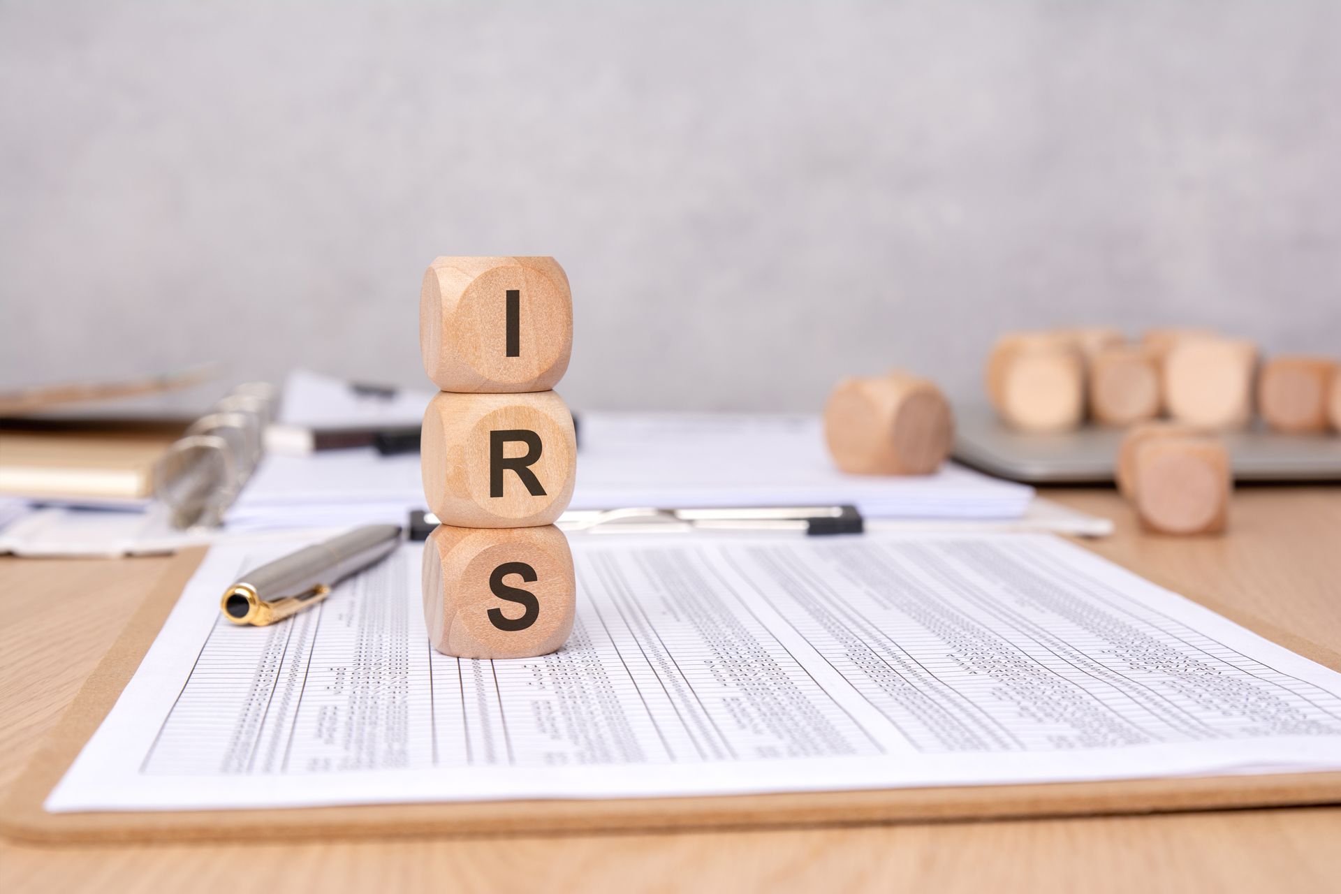 IRS letter tiles on paperwork beside a pen and calculator on a desk