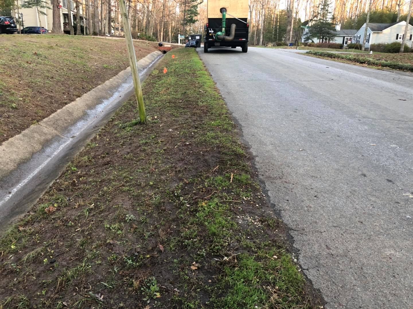 A truck is driving down a street next to a curb.